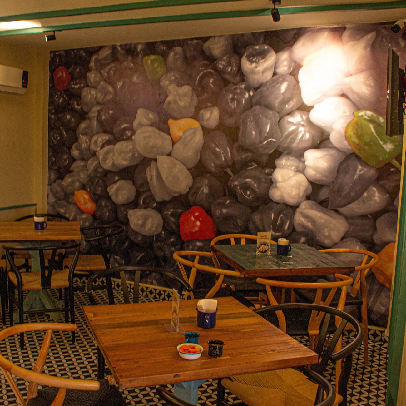 Interior de Pib-il con mural de chiles habaneros y mesas de madera